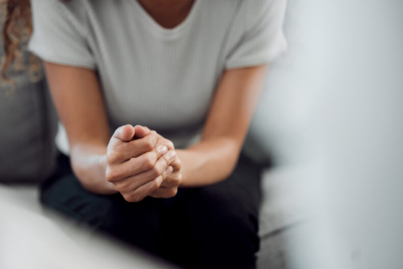 Woman sitting with her hands clasped together