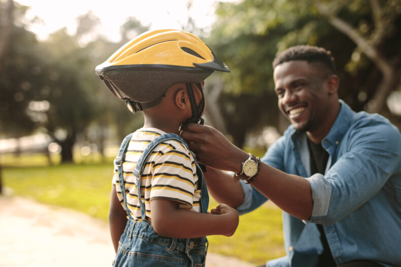 Father helping son put his bicycle helmet on