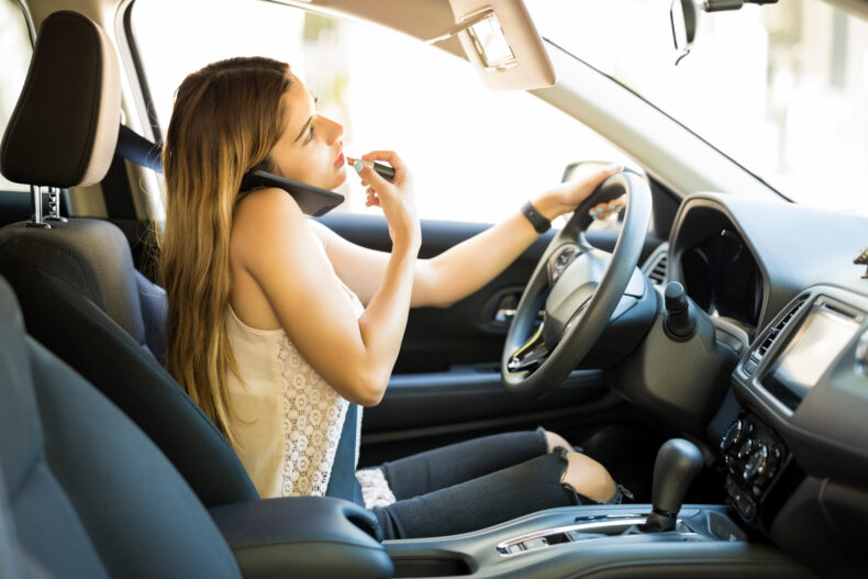 Woman applying lipstick while driving