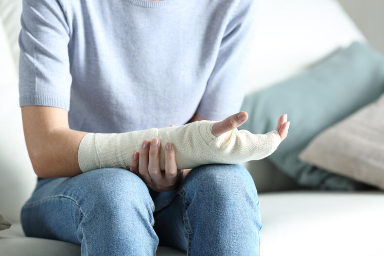 Person sitting holding their arm in a cast