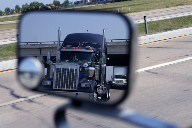 View of semi truck in side view mirror