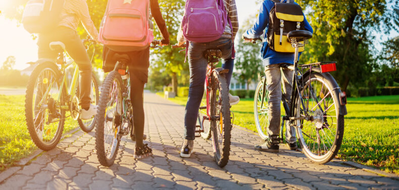 Four kids with backpacks riding bicycles