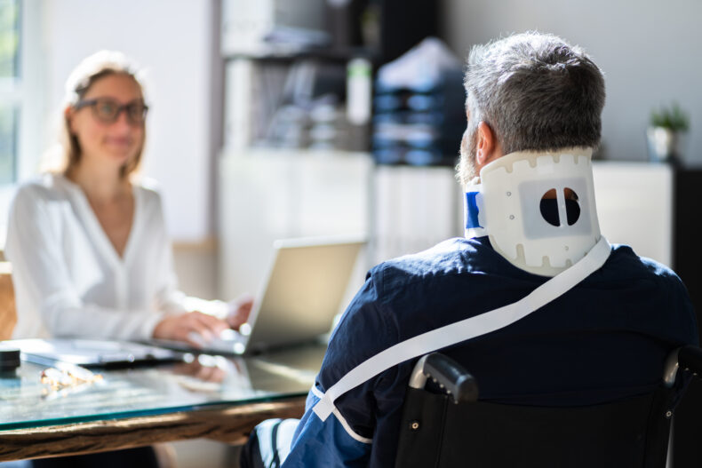 Man with a neck brace talking to an attorney