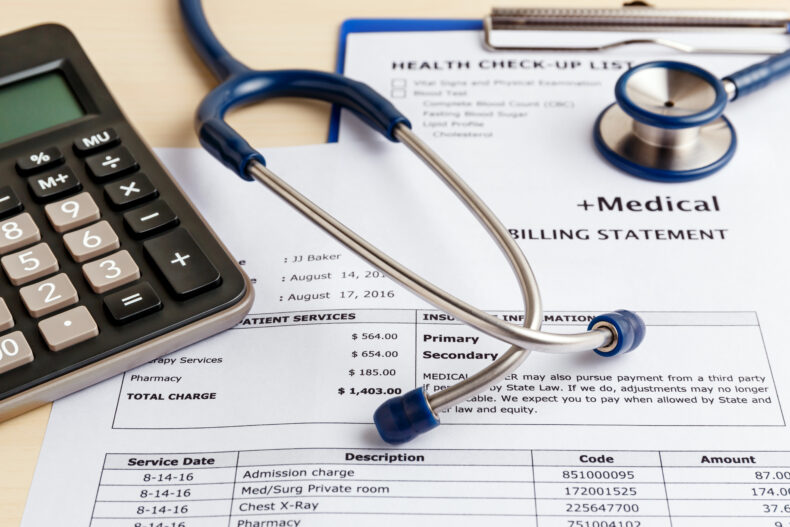 Stethoscope and calculator on top of medical bills