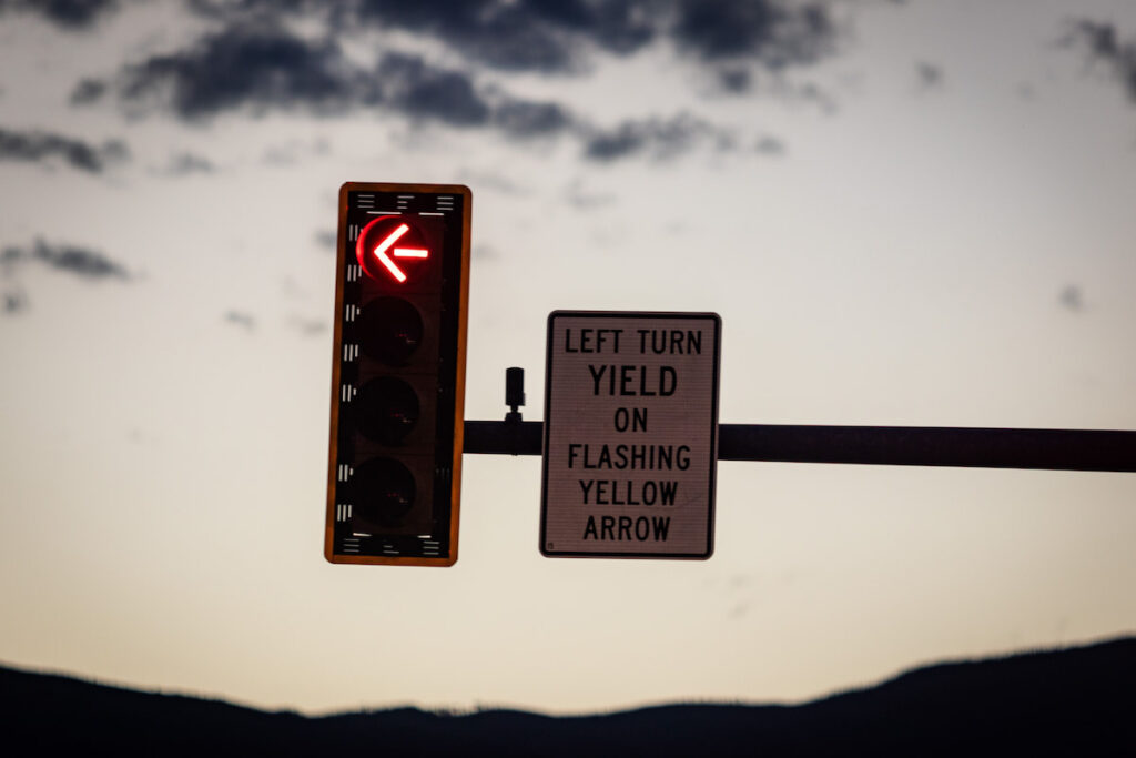 A closeup shot of a traffic light and sign indicating "left turn yield on flashing yellow arrow