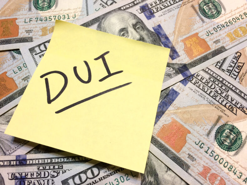 DUI written on a yellow post it on top of 100 dollar bills