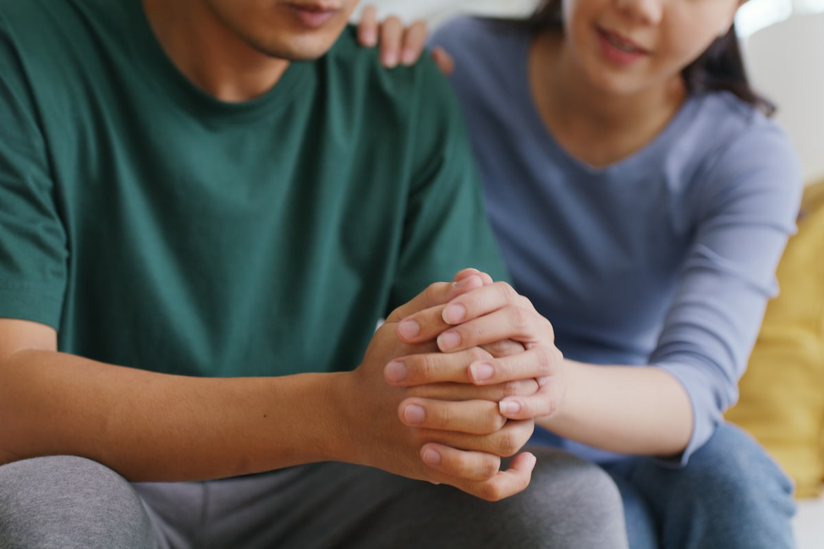 Man and woman holding hands while talking to each other and sitting on a sofa