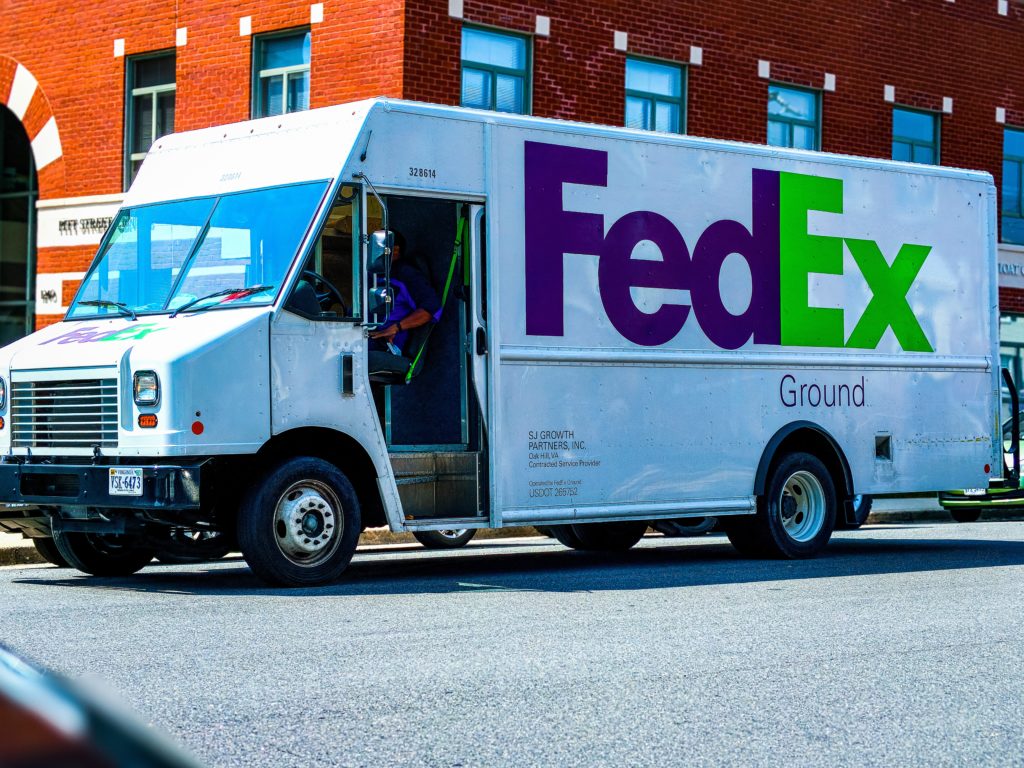 White FedEx truck in front of a red brick building