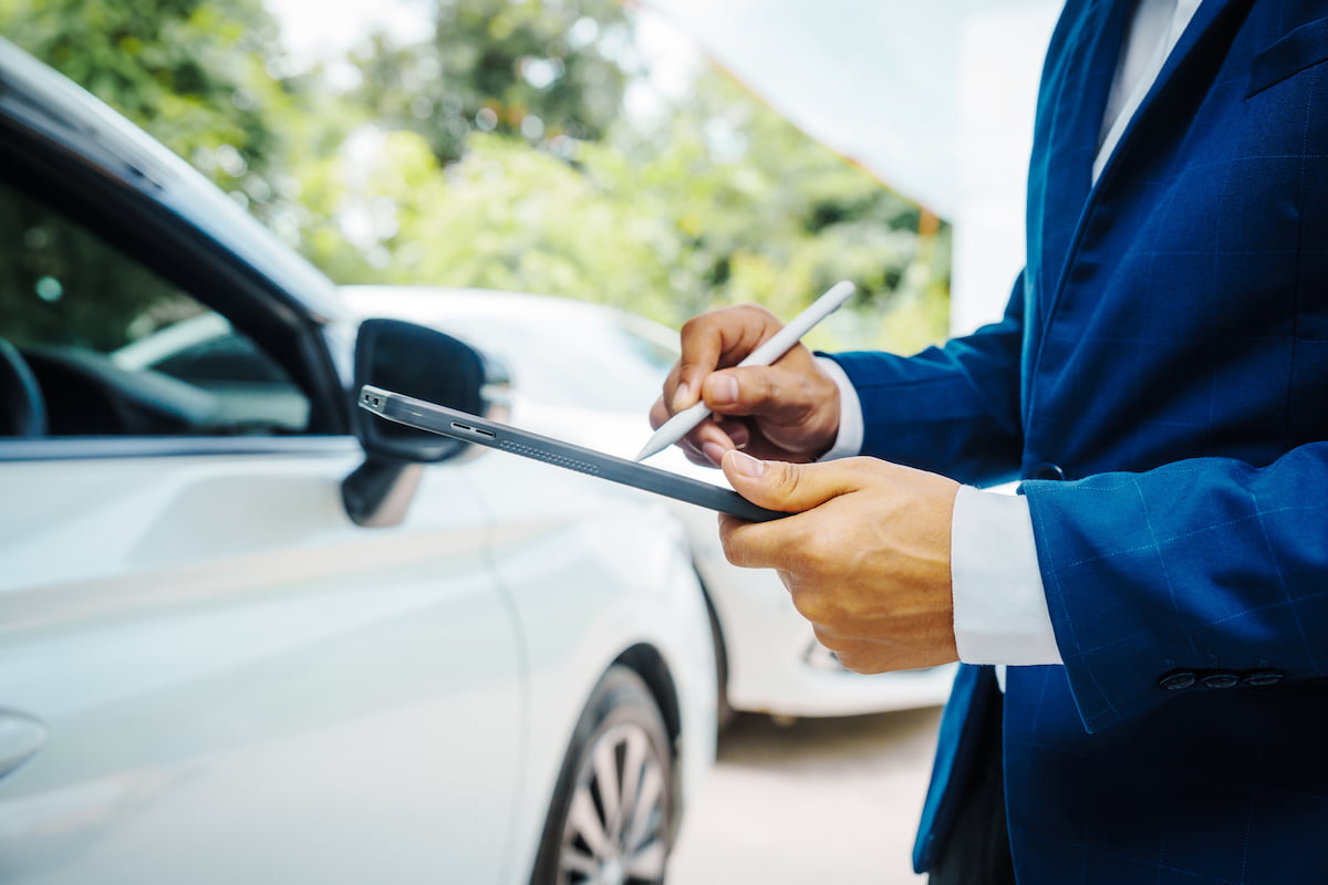 Insurance adjuster holding a clipboard and performing an appraisal on a vehicle