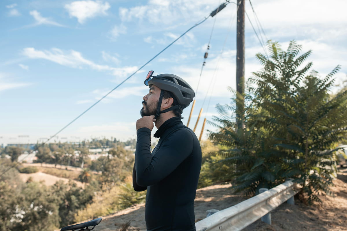 A man in a black shirt adjusting his bicycle helmet in Los Angeles.