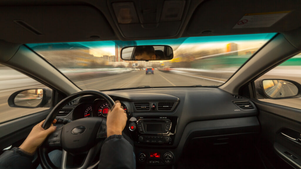 Driver going fast on highway. View from inside the car