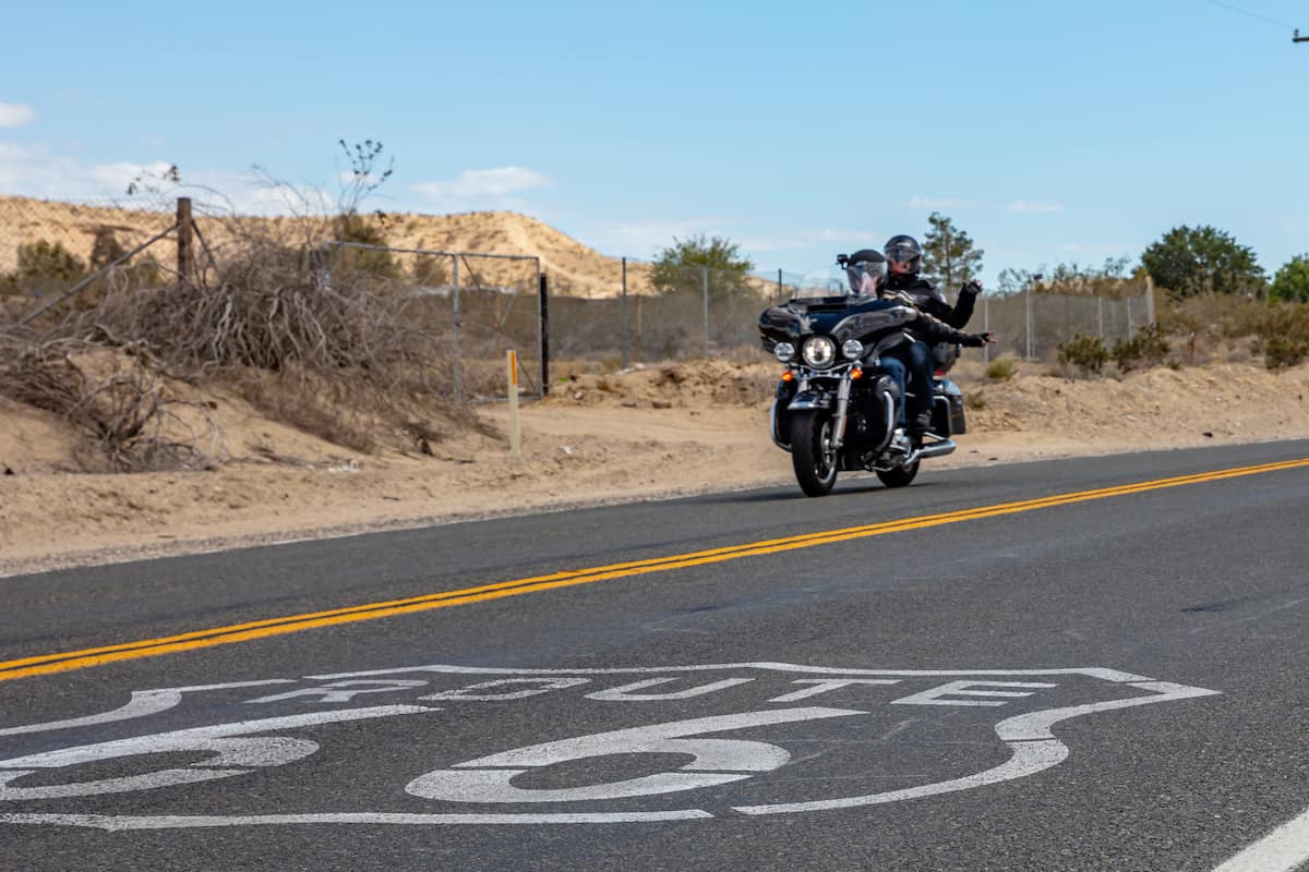 Young couple bikers riding a motorcycle on the historic route 66 highway, spring sunny day, USA.
