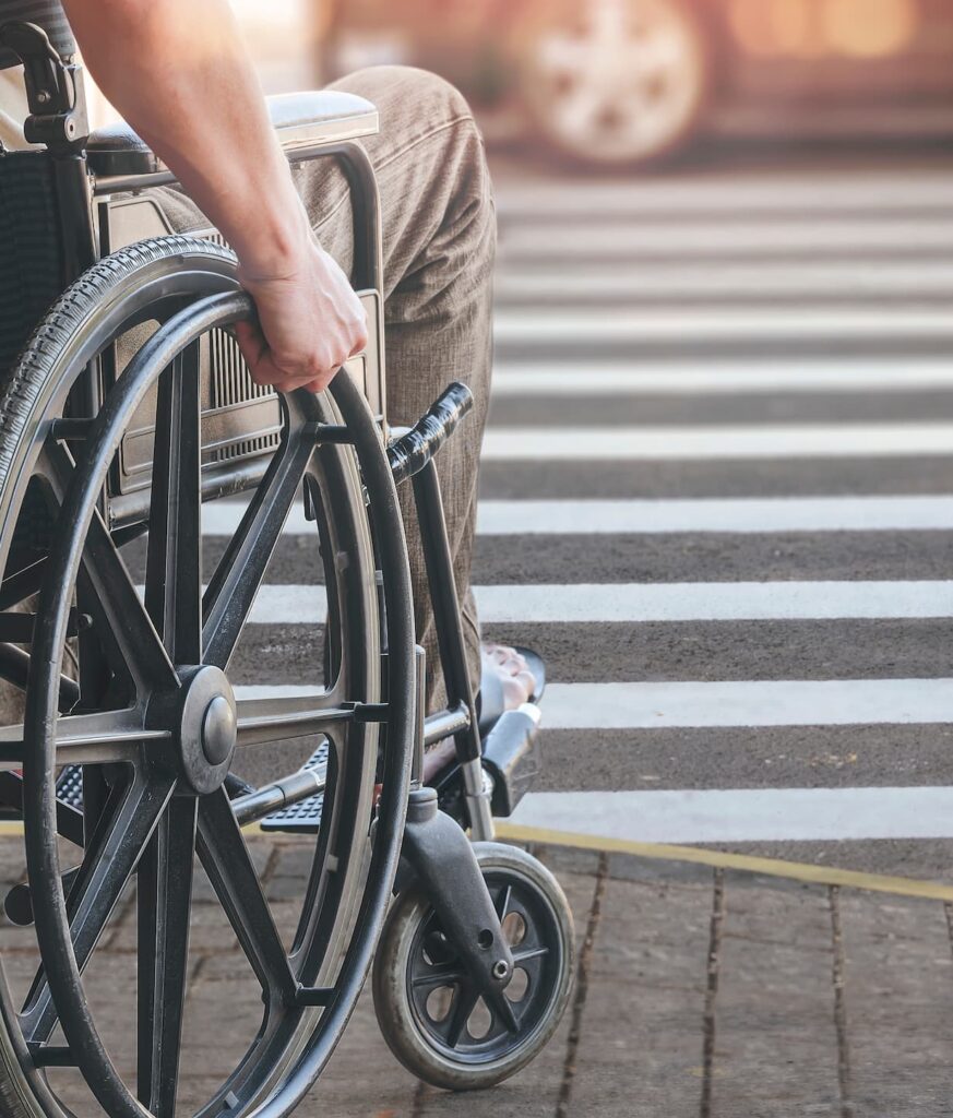 Hombre en silla de ruedas cruzando la calle por un paso de peatones,