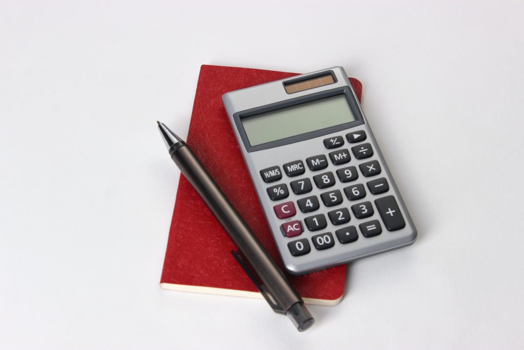 Calculator, notebook, and pen on white background