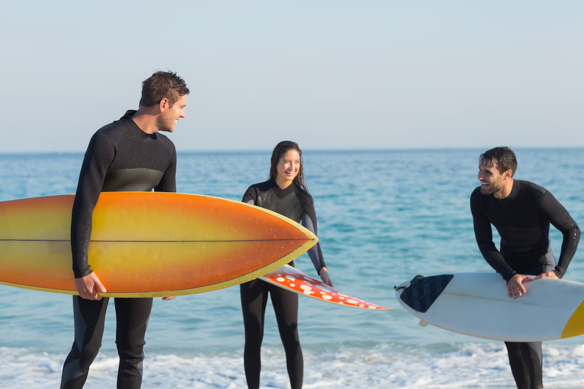 Surfistas sujetando sus tablas y conversando en la playa