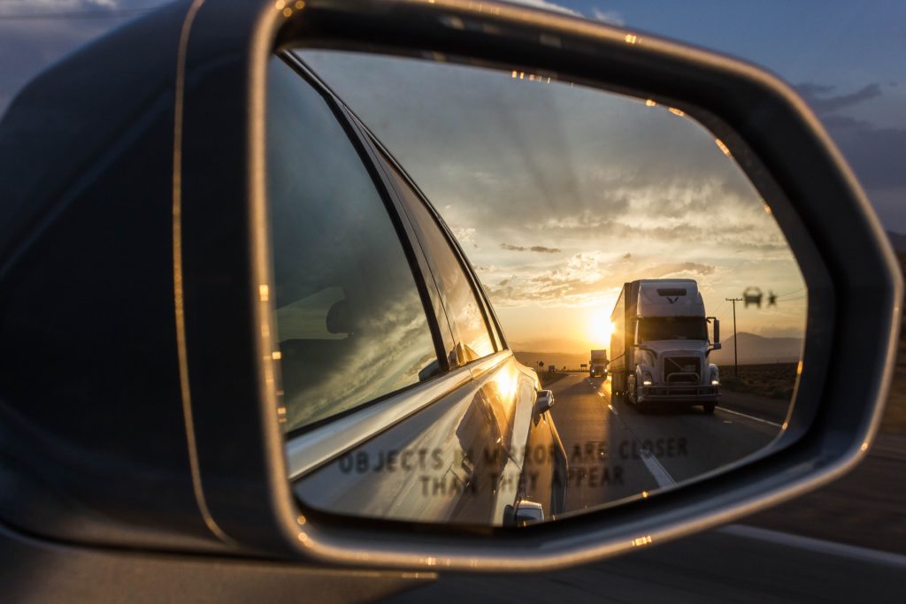 View of semi truck approaching from side mirror