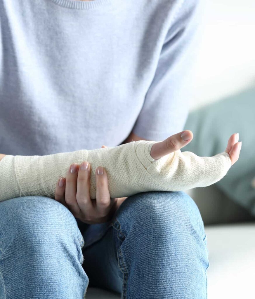 woman with a broken hand holding her arm cast.
