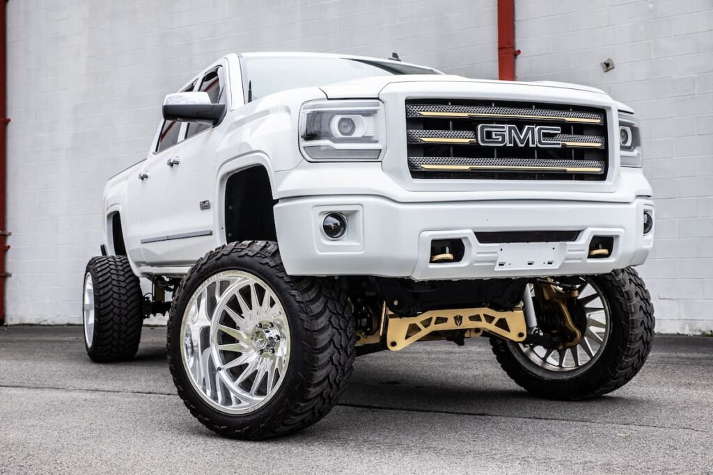 A white lifted GMC truck parked outdoors.