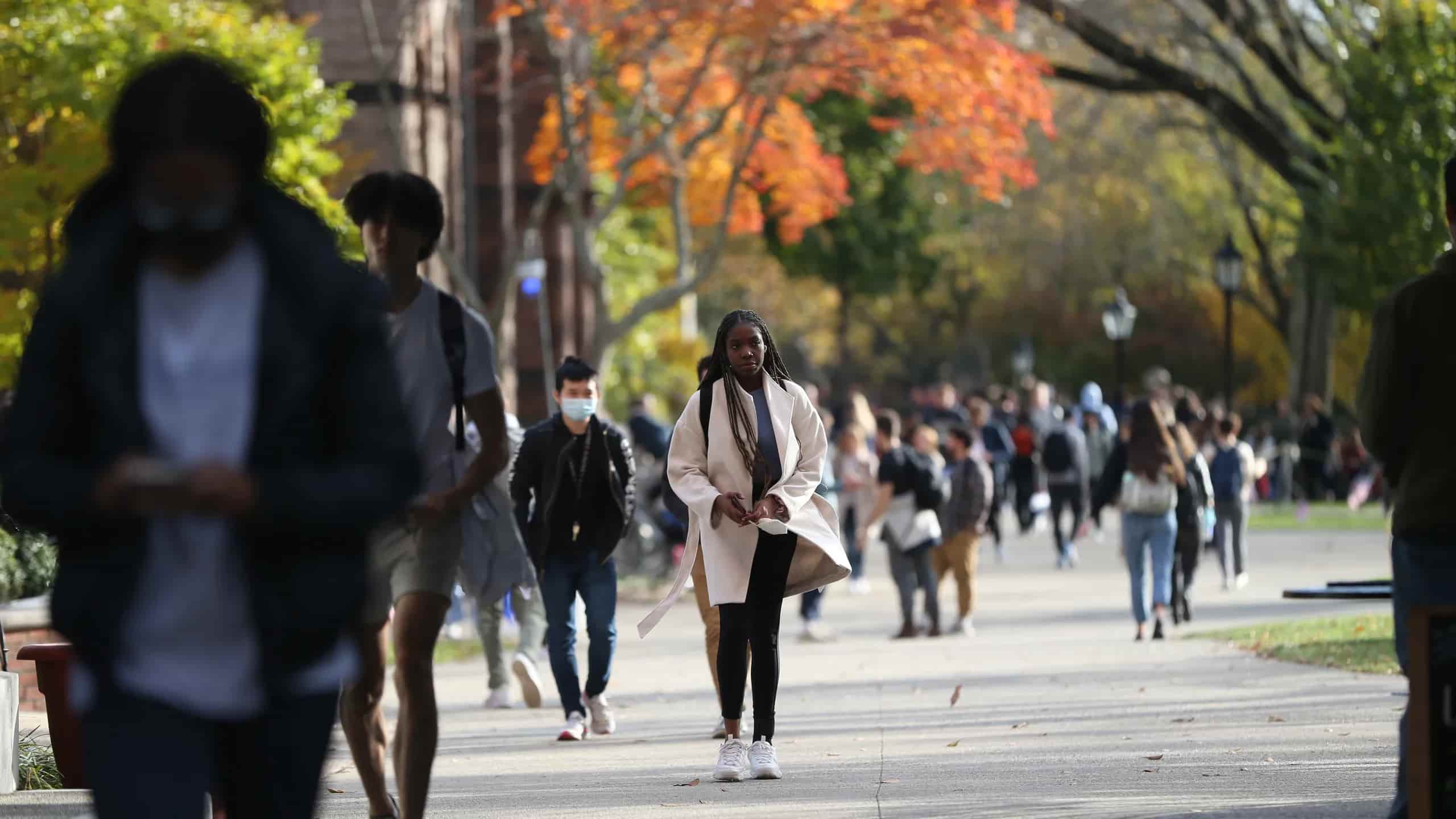 Students walking on campus with autumn trees in the background