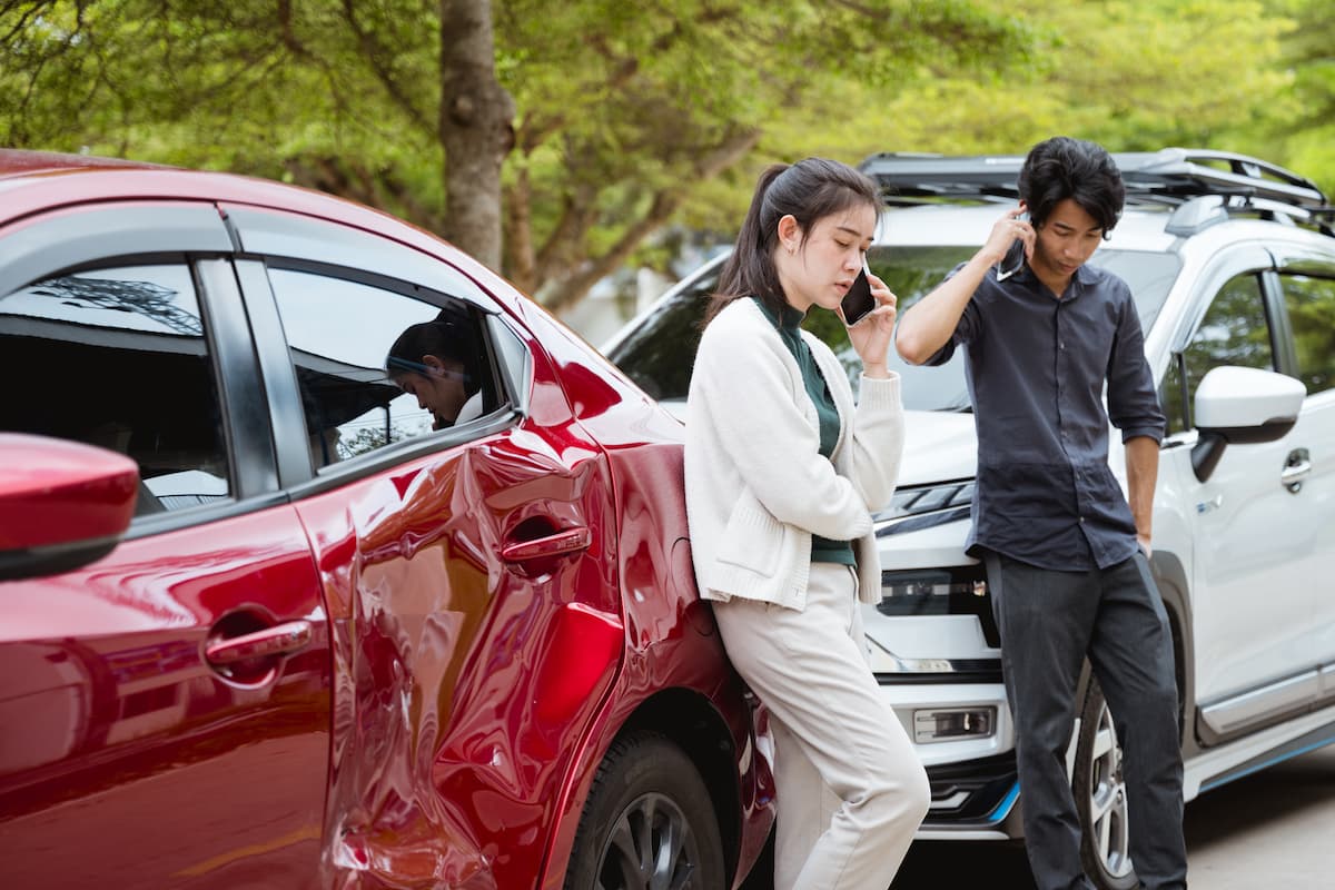 Drivers looking distressed next to damaged vehicles