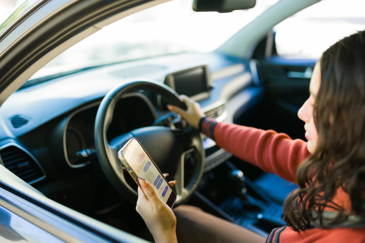 Female teenage driver using a smartphone while behind the wheel