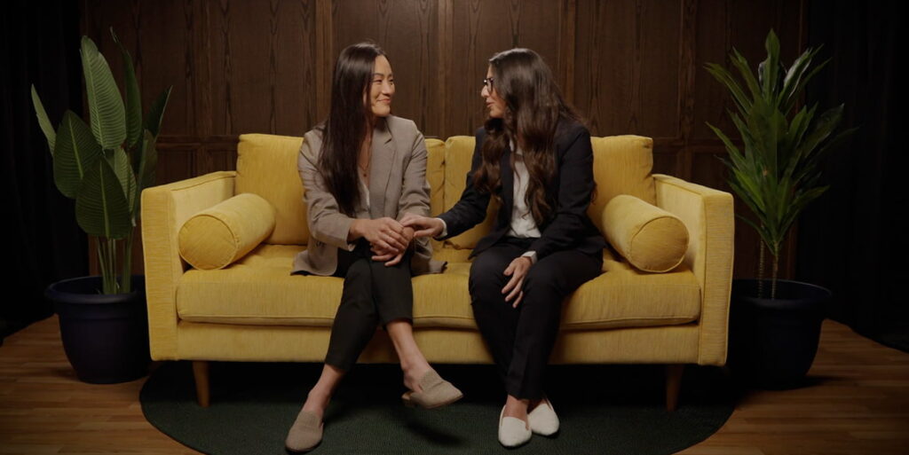 Two women sitting on a mustard yellow couch