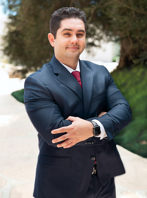 personal injury attorney in a blue suit and red tie standing in an exterior setting