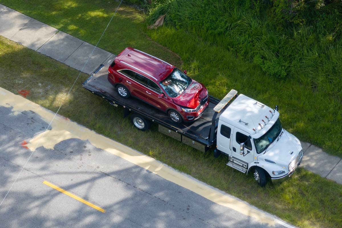 Tow truck hauling smashed vehicle on car accident site.