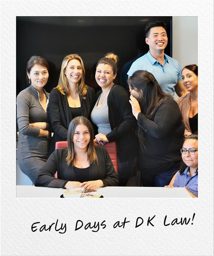 Group photo of the early DK Law team, smiling together in an office setting, with handwritten text at the bottom reading 'Early Days at DK Law!