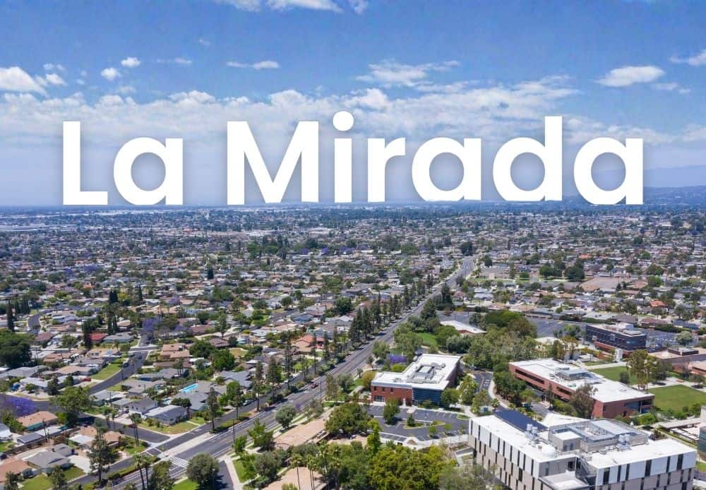 Aerial view of La Mirada with residential neighborhoods, streets, and buildings under a clear blue sky.