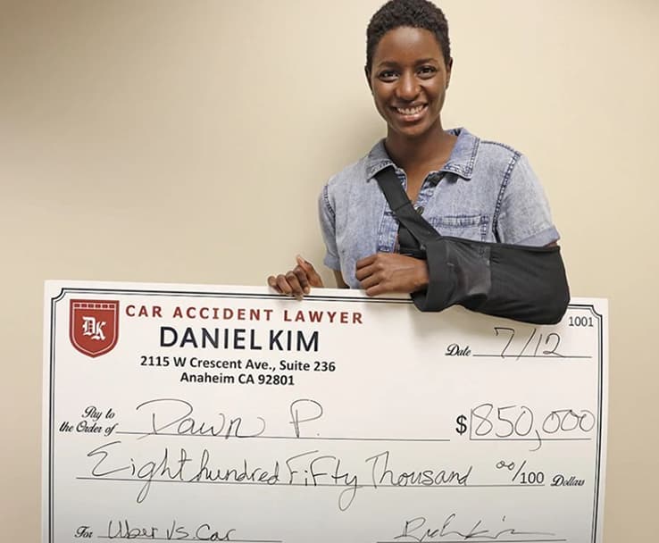 DK Law Client Image with a Jumbo Check of $850,000 for an Uber vs Car Case