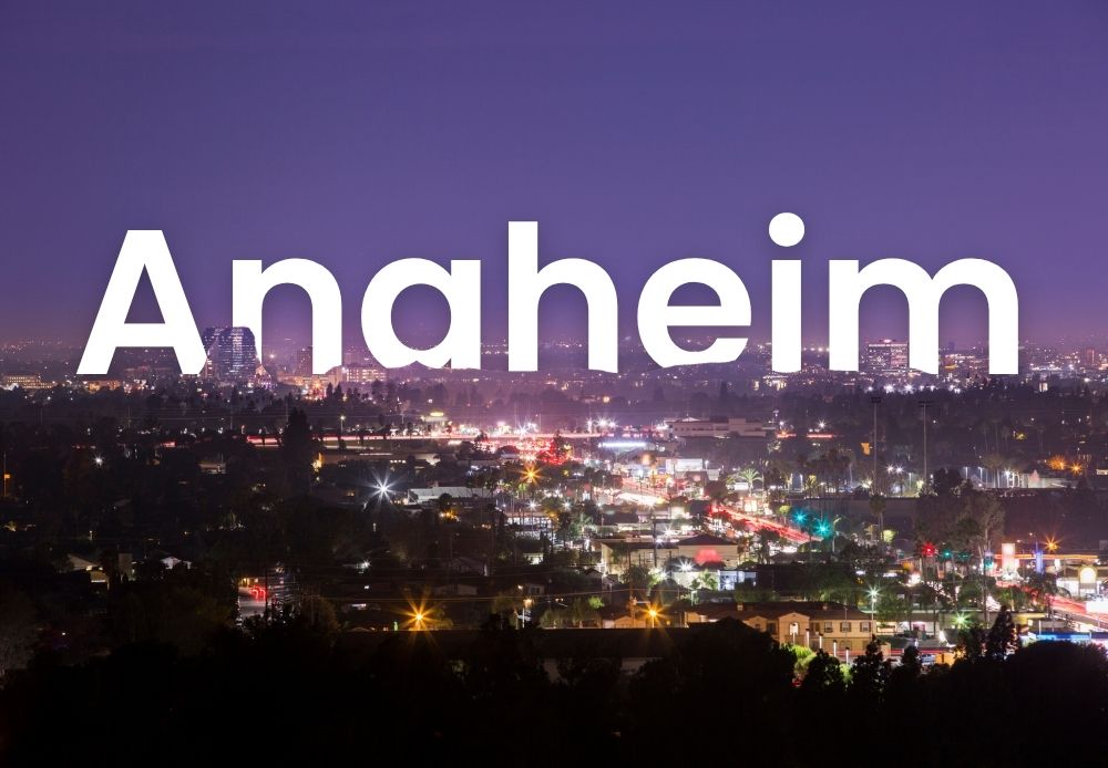 Night view of Anaheim city with illuminated streets, traffic lights, and skyline under a purple evening sky.