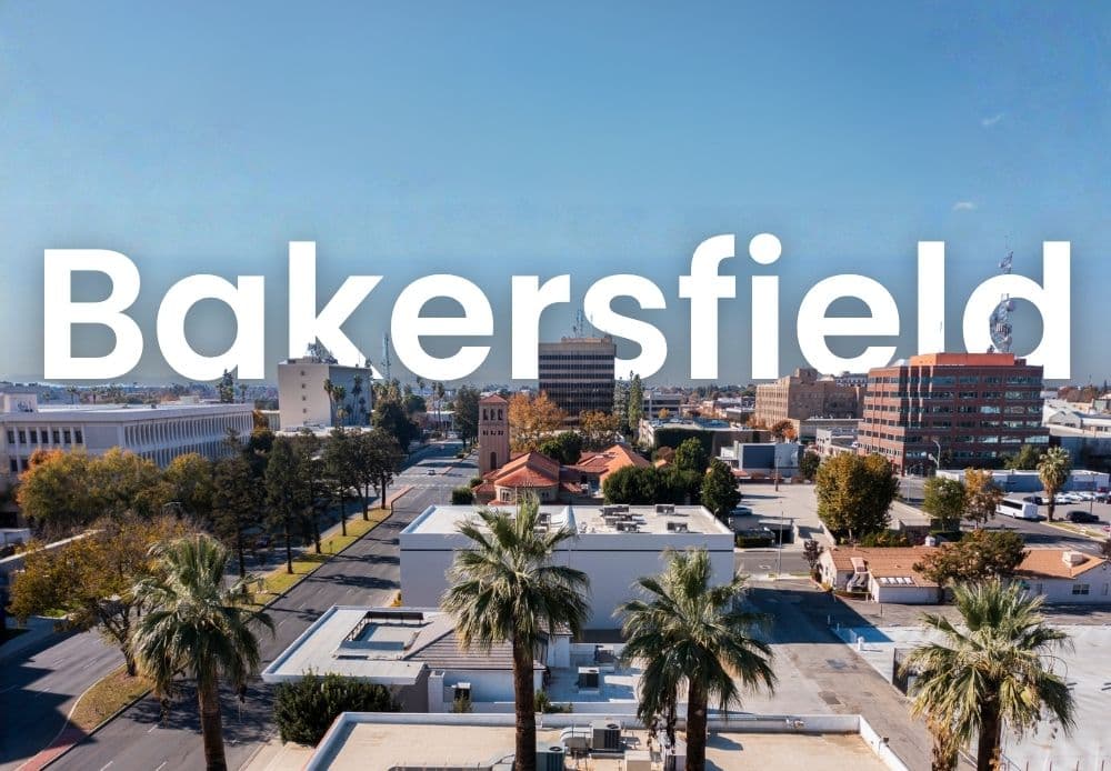Aerial view of downtown Bakersfield with palm-lined streets and city buildings under a clear blue sky.