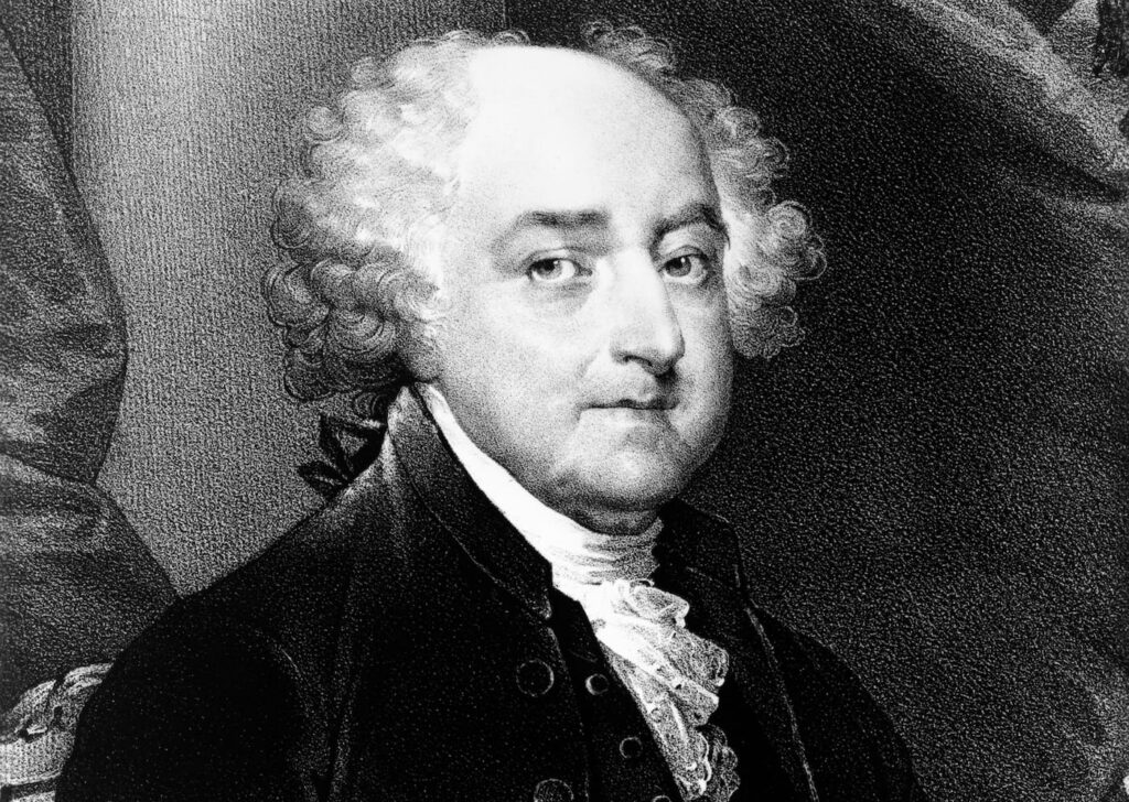 A black and white engraved portrait of John Adams (1735–1826), Founding Father and second President of the United States. He is depicted in 18th-century attire, wearing a dark coat with a ruffled white cravat and powdered curly hair, with a composed and serious expression.
