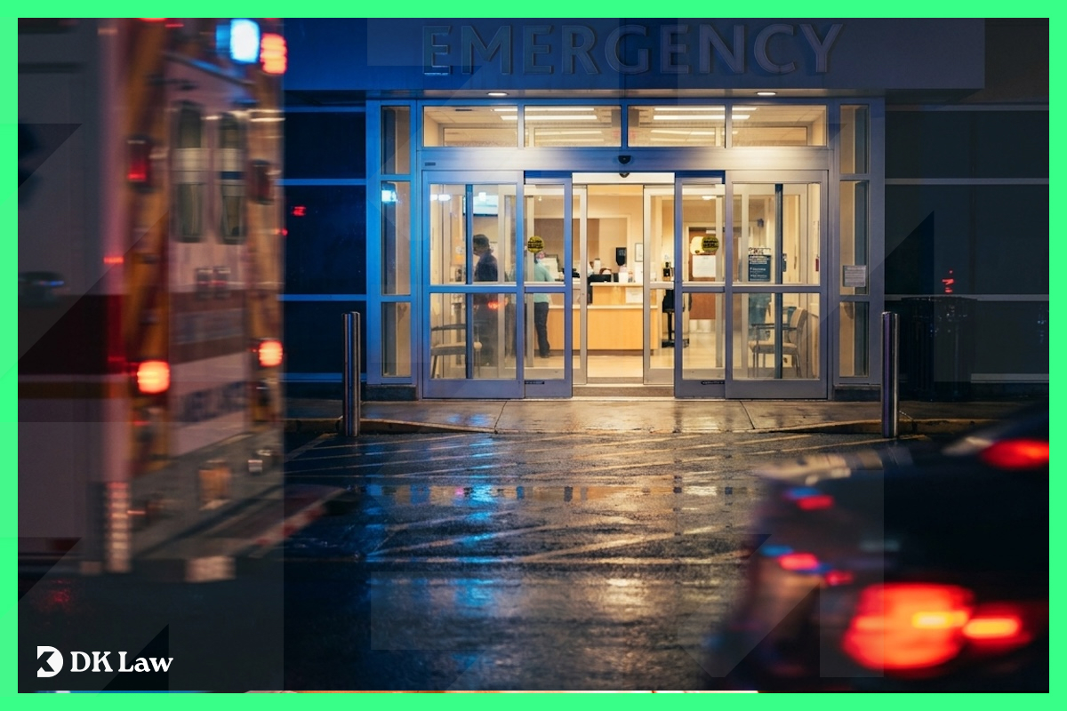 A hospital emergency room entrance illuminated at night with ambulance lights reflecting off a wet pavement, representing the decision to seek emergency medical care after a car accident