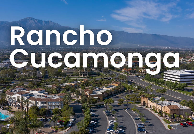 Aerial view of downtown Rancho Cucamonga with mountains in the background and large white text reading “Rancho Cucamonga.”